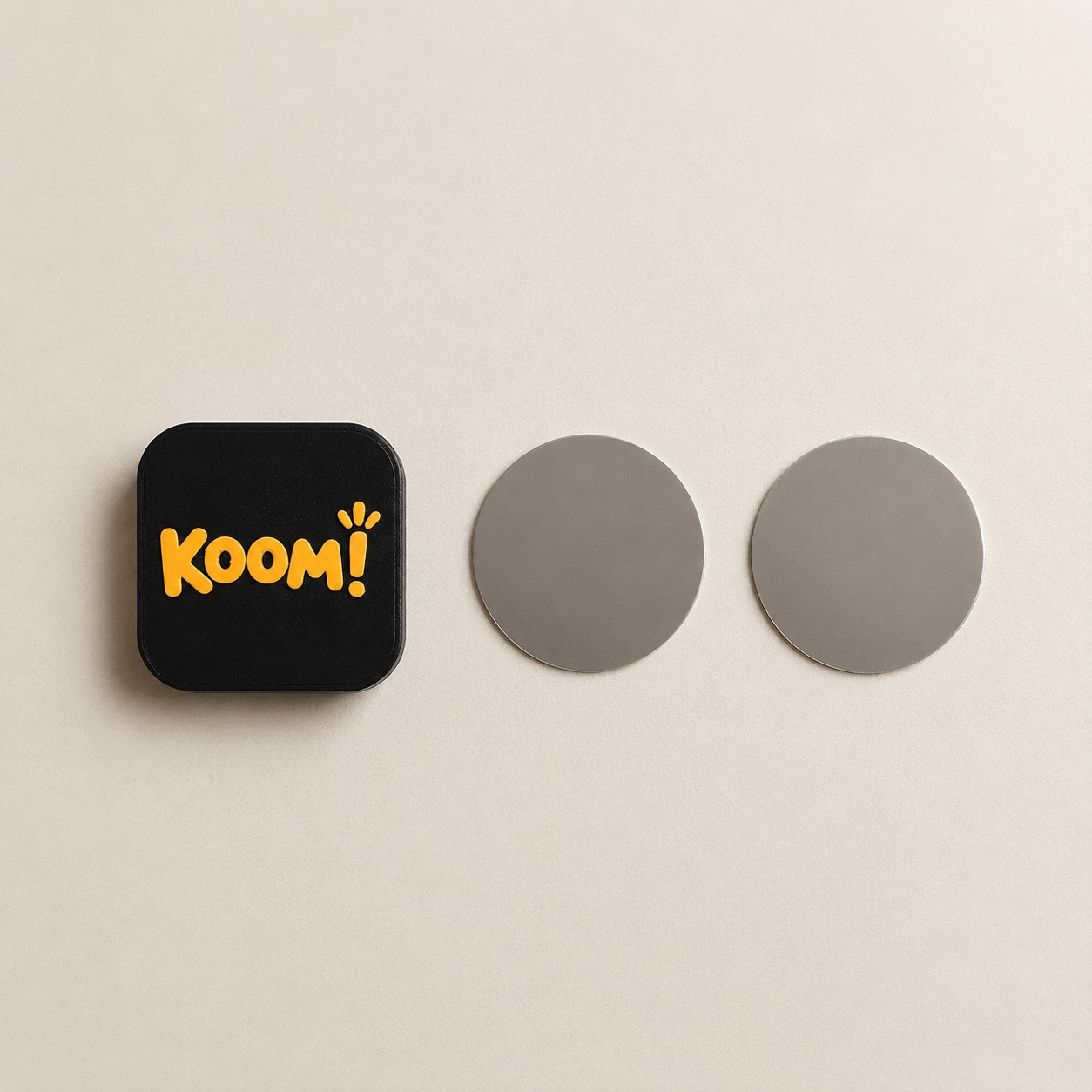 מה מגיע בקופסה: תג Koom!‎ ושתי לוחיות מתכת עגולות להצמדה לקיר